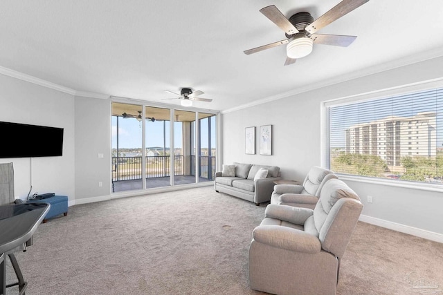 living area with a ceiling fan, light colored carpet, crown molding, and baseboards