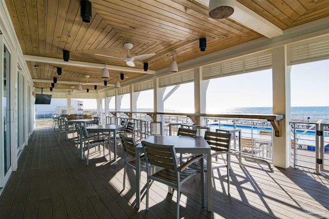 wooden terrace with a ceiling fan, outdoor dining space, and a water view