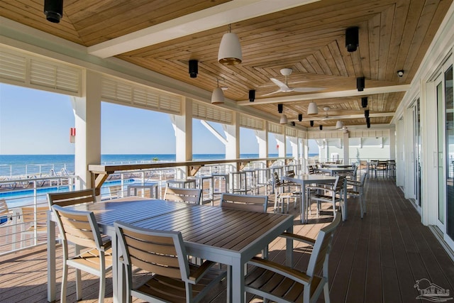 deck with a ceiling fan, outdoor dining space, and a water view