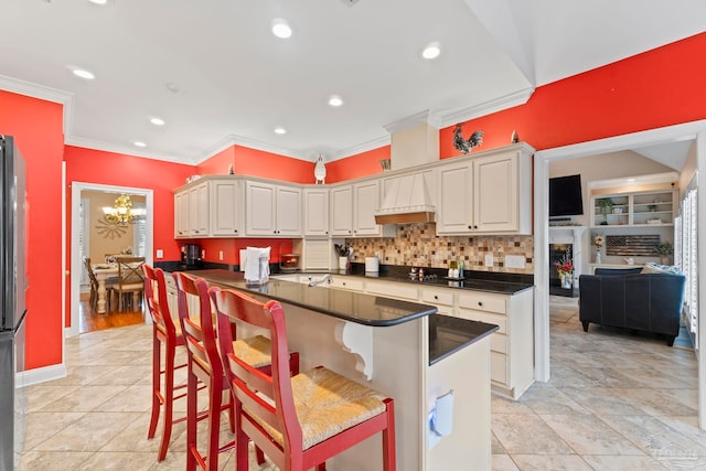 kitchen featuring a kitchen bar, tasteful backsplash, ornamental molding, custom range hood, and white cabinets