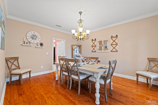 dining area featuring crown molding, wood-type flooring, and a chandelier