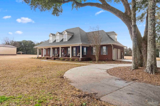 cape cod home with a garage, a front yard, and a porch