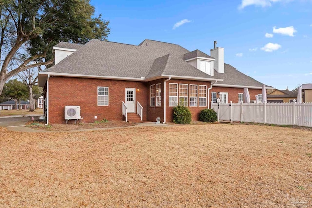 back of property with ac unit and a lawn