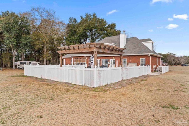 rear view of house with a yard and a pergola