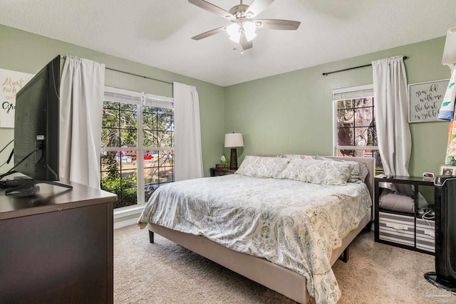 bedroom featuring ceiling fan, light carpet, and a textured ceiling