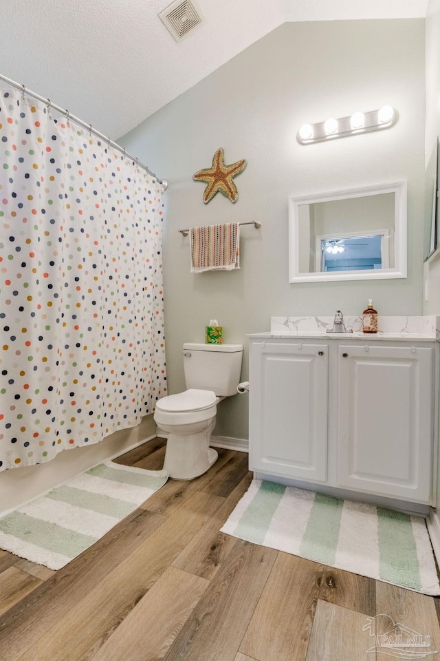 bathroom with toilet, vanity, vaulted ceiling, walk in shower, and hardwood / wood-style floors