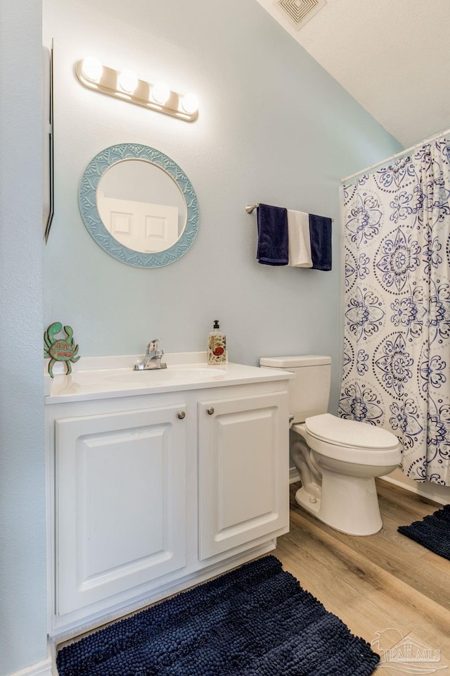 bathroom featuring toilet, vanity, and hardwood / wood-style flooring