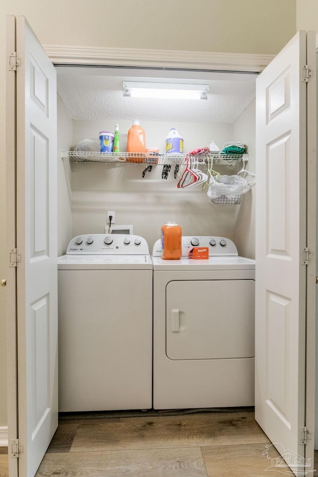 clothes washing area with a textured ceiling, light wood-type flooring, and washing machine and clothes dryer