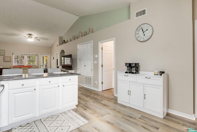 kitchen featuring ceiling fan, white cabinetry, lofted ceiling, and light hardwood / wood-style floors