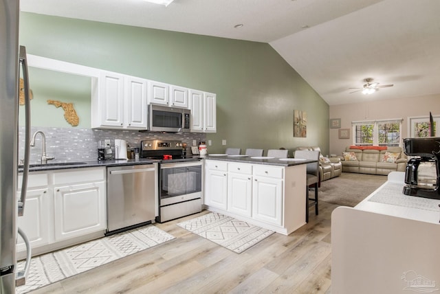 kitchen with tasteful backsplash, kitchen peninsula, sink, stainless steel appliances, and white cabinets