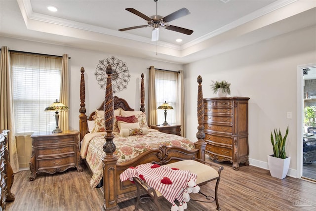 bedroom with a tray ceiling, hardwood / wood-style floors, crown molding, and ceiling fan