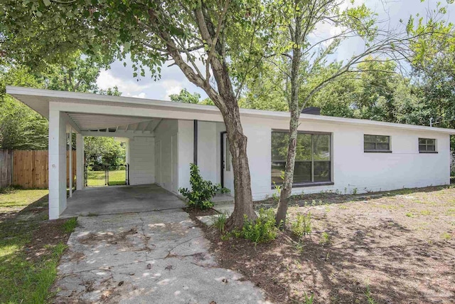 view of front of home with an attached carport, fence, and stucco siding