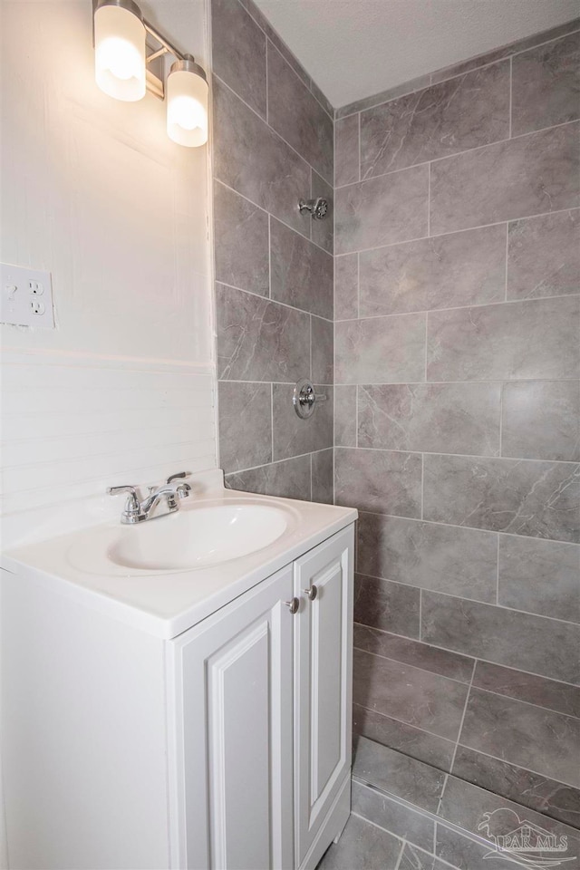 bathroom featuring tile walls, tile patterned floors, vanity, and a shower