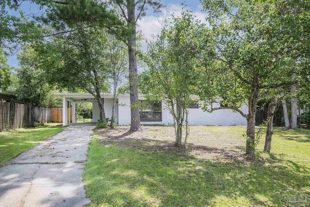 view of front facade with a carport, a front yard, fence, and driveway