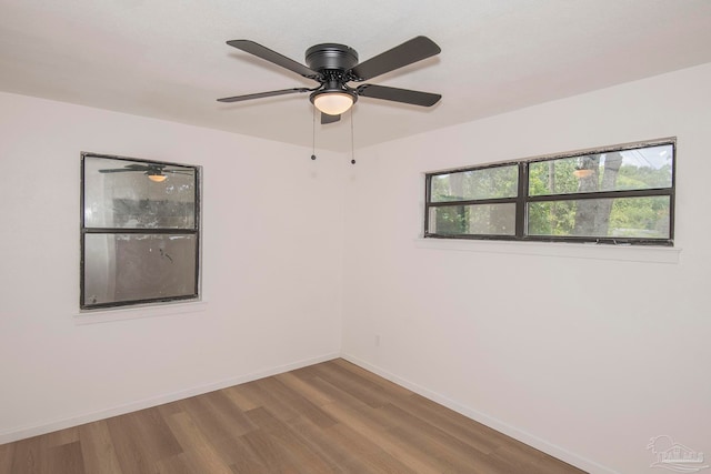 unfurnished room featuring a healthy amount of sunlight, wood-type flooring, and ceiling fan