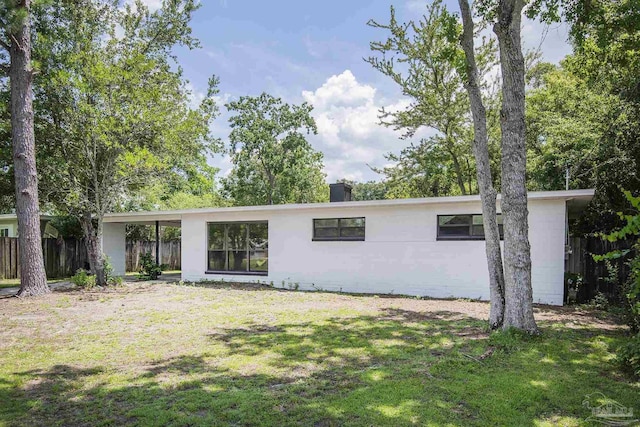 60 Stanford Rd, Pensacola, FL 32506 - back of property featuring a yard, concrete block siding, fence, and a chimney