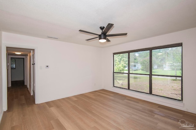 empty room with a healthy amount of sunlight, light hardwood / wood-style flooring, and ceiling fan