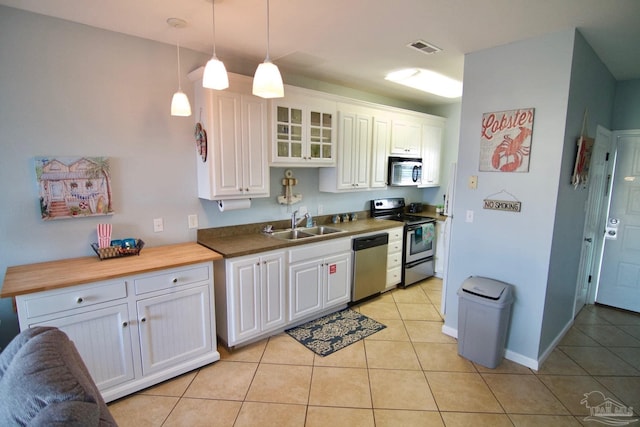 kitchen with white cabinets, light tile patterned flooring, decorative light fixtures, and stainless steel appliances