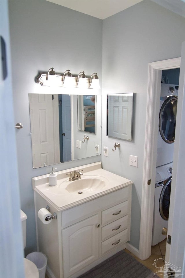 bathroom featuring stacked washing maching and dryer, vanity, and toilet