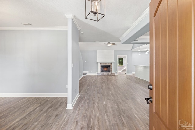 unfurnished living room featuring a textured ceiling, crown molding, wood-type flooring, and a fireplace