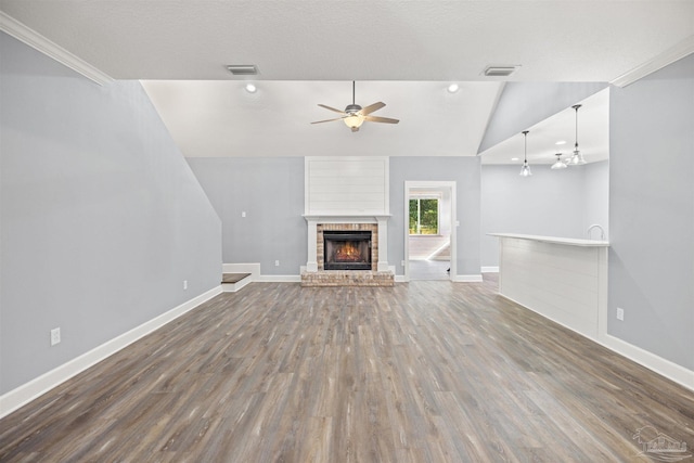 unfurnished living room with a brick fireplace, dark hardwood / wood-style flooring, vaulted ceiling, and ceiling fan