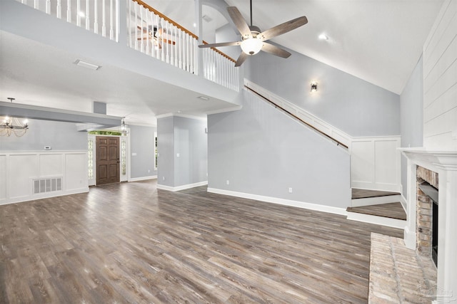 unfurnished living room featuring hardwood / wood-style floors, ceiling fan with notable chandelier, a fireplace, and high vaulted ceiling