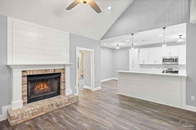 unfurnished living room with high vaulted ceiling, dark hardwood / wood-style floors, a brick fireplace, and ceiling fan