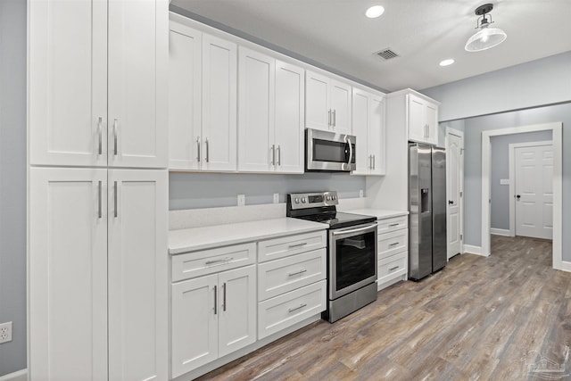 kitchen featuring wood-type flooring, white cabinetry, and stainless steel appliances