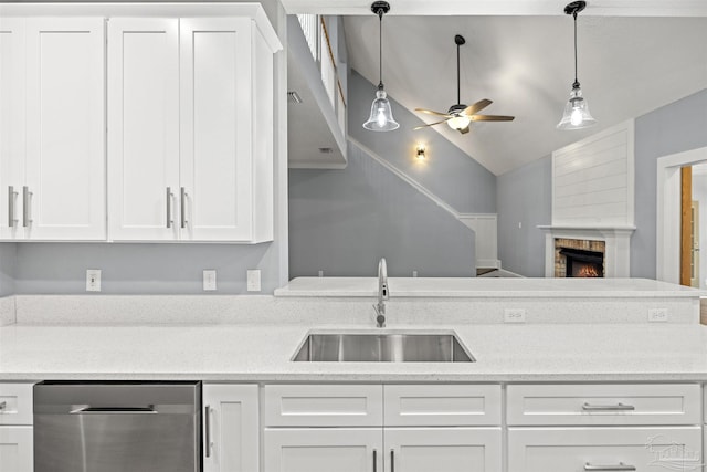 kitchen featuring white cabinetry, dishwasher, sink, lofted ceiling, and a fireplace