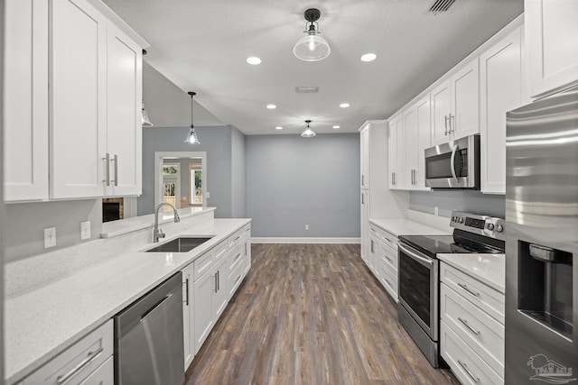 kitchen featuring sink, white cabinets, decorative light fixtures, and appliances with stainless steel finishes