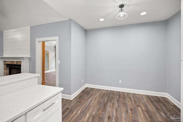 interior space featuring a brick fireplace, a textured ceiling, dark hardwood / wood-style floors, and white cabinetry