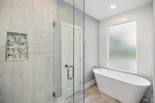 bathroom featuring plus walk in shower and hardwood / wood-style flooring