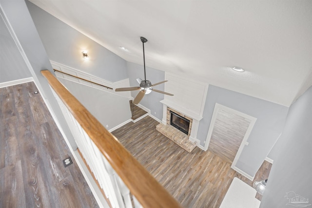 stairs with wood-type flooring, a brick fireplace, ceiling fan, and lofted ceiling