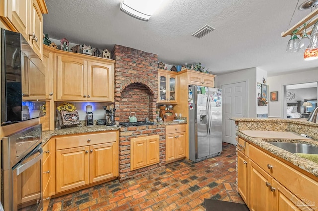 6552 Emerald Forest Dr, Milton, FL 32570 - kitchen featuring stainless steel appliances, brick flooring, glass insert cabinets, a textured ceiling, and light stone counters