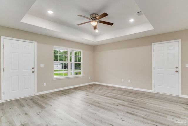 interior space with light wood-type flooring, a raised ceiling, and ceiling fan