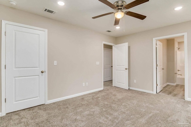 unfurnished bedroom with light colored carpet, ensuite bath, and ceiling fan