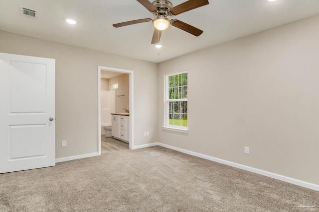 unfurnished bedroom featuring ensuite bathroom, ceiling fan, and light carpet