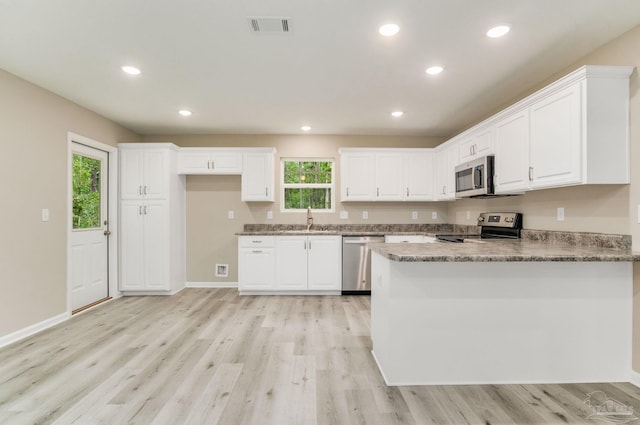 kitchen with plenty of natural light, white cabinetry, sink, and appliances with stainless steel finishes