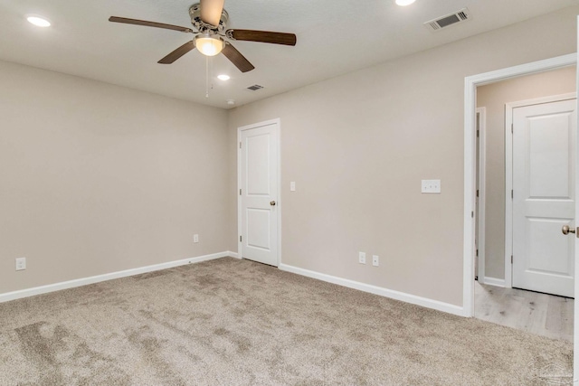 spare room with ceiling fan and light colored carpet