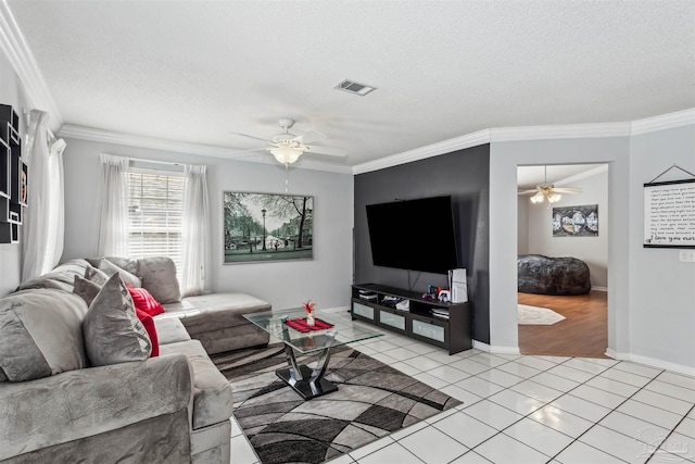 tiled living room with a textured ceiling, ceiling fan, and ornamental molding