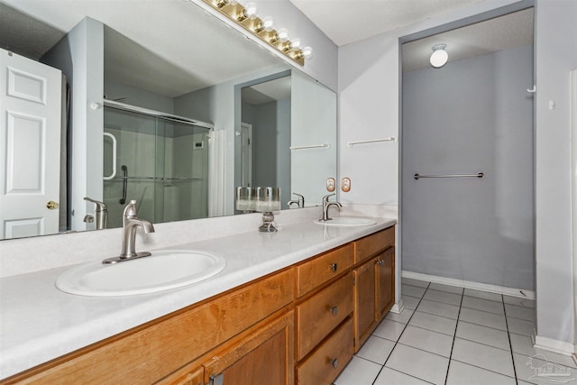 bathroom with a shower with shower door, vanity, and tile patterned floors