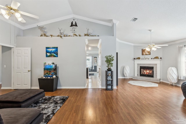 living room featuring lofted ceiling, a fireplace, crown molding, and hardwood / wood-style floors