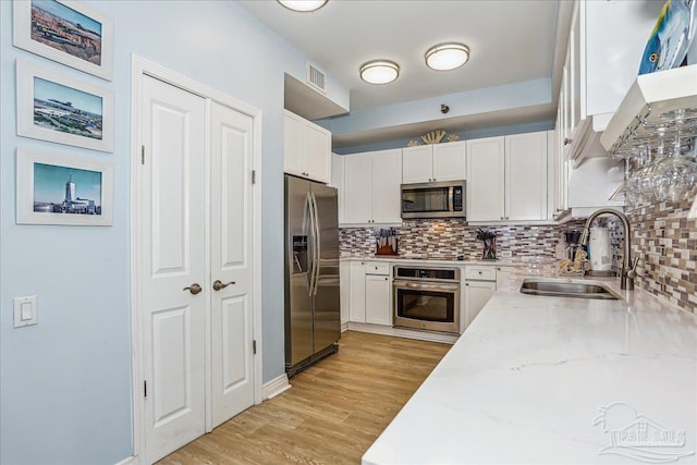 13599 Perdido Key Dr Unit T-2C, Perdido Key, FL 32507 - kitchen featuring stainless steel appliances, white cabinetry, light stone countertops, backsplash, and light wood-style flooring