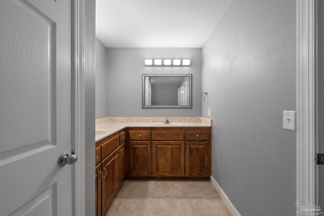 bathroom with double vanity, tile patterned floors, baseboards, and a sink