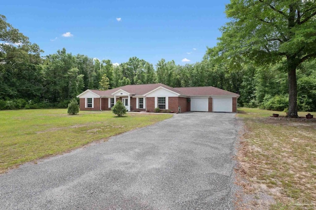 single story home with a view of trees, aphalt driveway, a front yard, and a garage