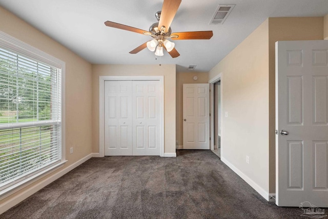 unfurnished bedroom featuring visible vents, baseboards, a closet, and dark colored carpet