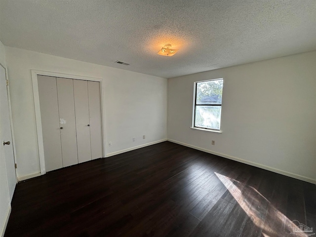 unfurnished bedroom featuring dark hardwood / wood-style floors, a textured ceiling, and a closet