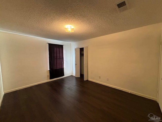 empty room featuring a textured ceiling and dark hardwood / wood-style floors