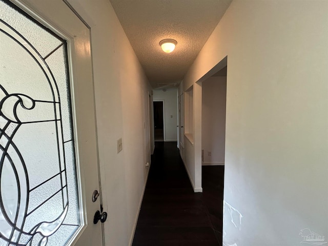 hallway featuring dark hardwood / wood-style flooring and a textured ceiling