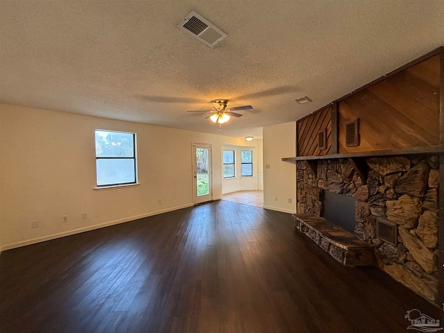 unfurnished living room featuring a textured ceiling, a fireplace, ceiling fan, and dark wood-type flooring